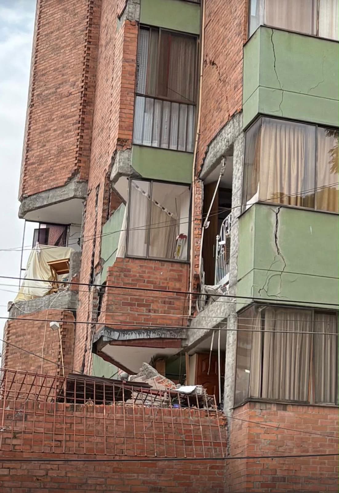Entrada del edificio acordonada con cinta amarilla y escombros en el andén